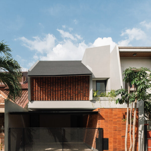DDD Residence in Karawaci – A stunning collaboration with architect Dhaniesal, featuring a contemporary design that combines sleek modern architecture with natural elements. The façade showcases a beautiful blend of textured brickwork and minimalist white walls, framed by lush greenery and a geometric fence, creating a welcoming yet stylish residential space.